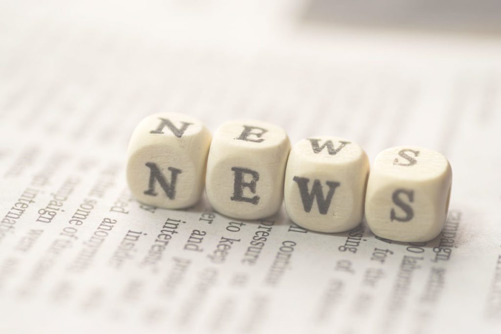 Four dice with the letters N.E.W.S on a newspaper image for Boyletts Law shortlisted at British Wills and Probate Awards 2021