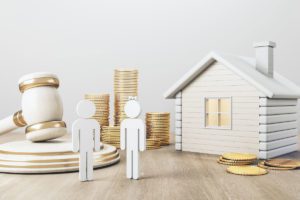 Illustration of couple outside a house with a pile of coins and a gavel image for what happens to my will after marriage or divorce blog